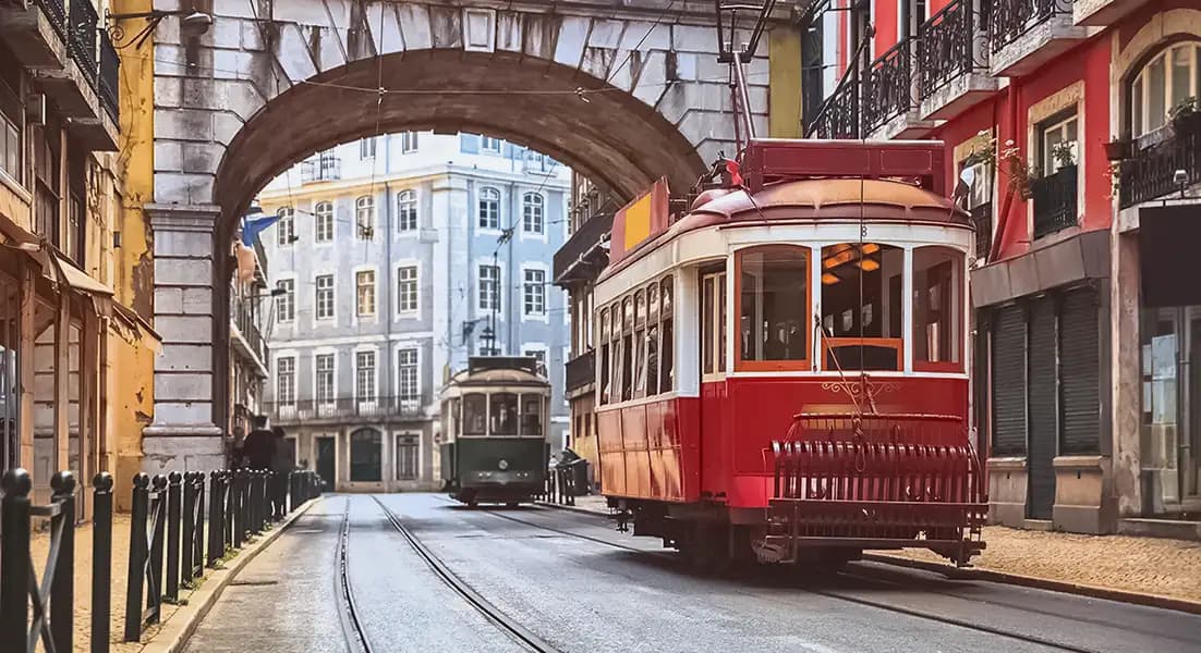 Red tram in Lisbon near Cais do Sodré passing under a stone arch