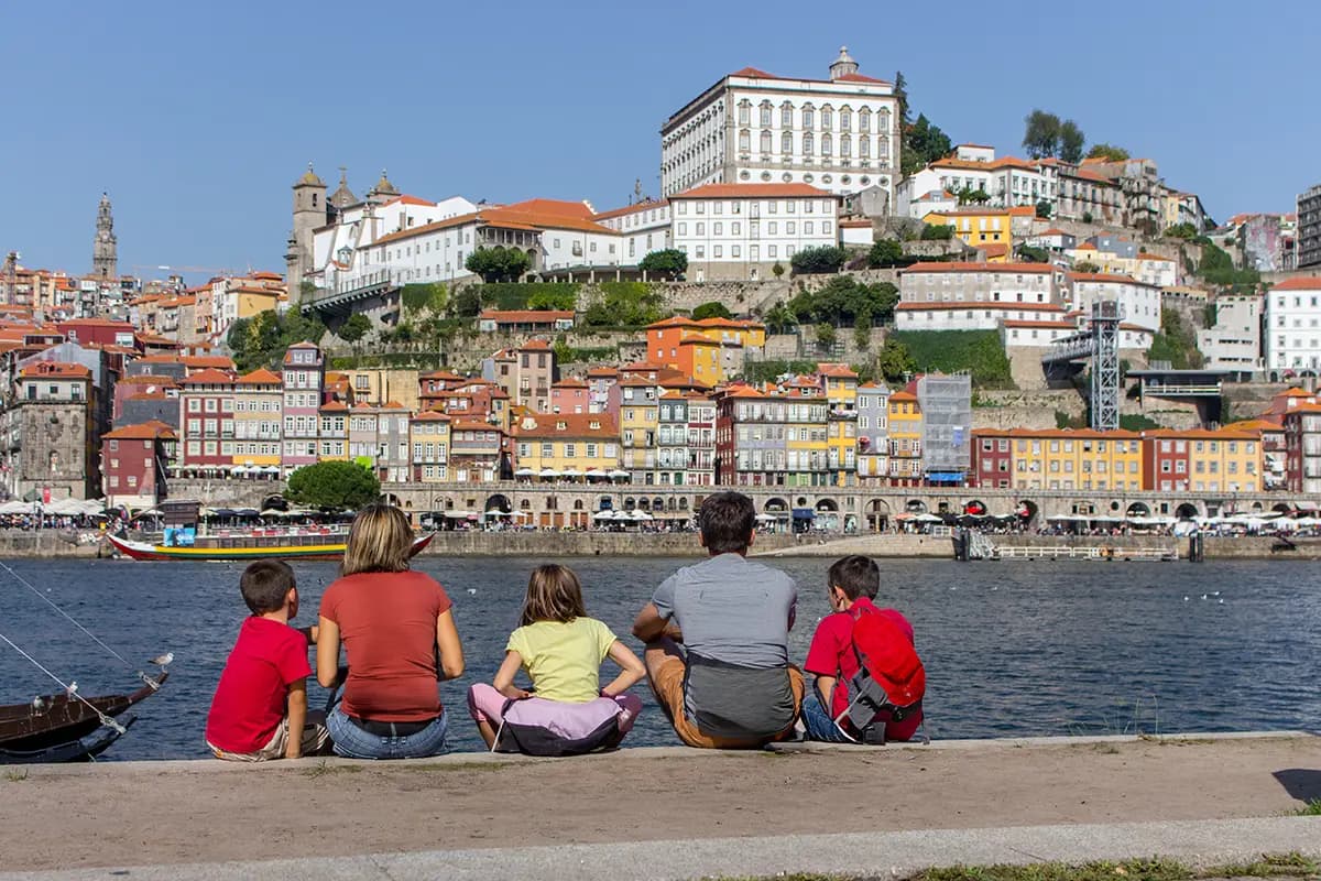Family living in Porto, parents and children sitting by the Ribeira.