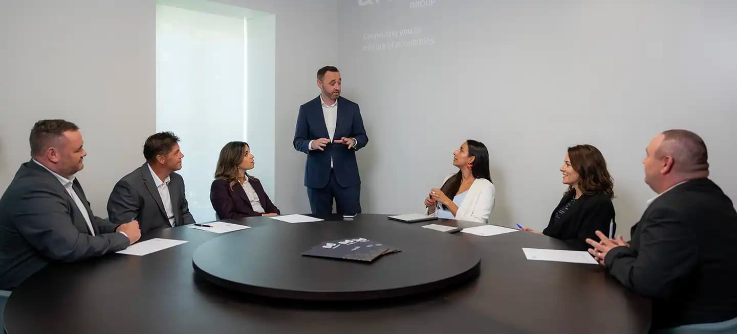 Business meeting with executives discussing strategy around a round table at Harland & Poston Group headquarters.