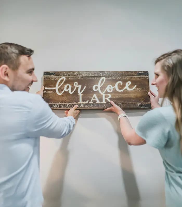Smiling couple placing a wooden "home sweet home" plate in their new house