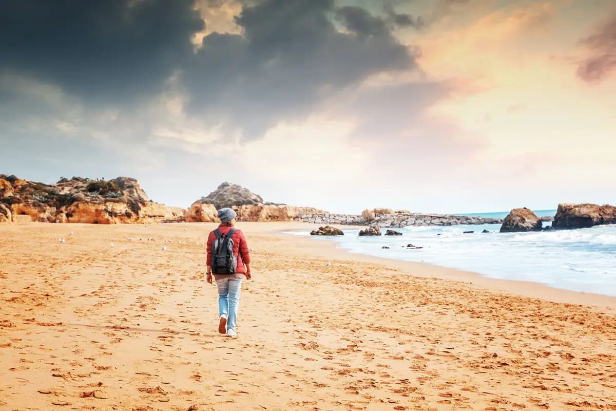 Person walking down a beach in the Algarve during the winter.
