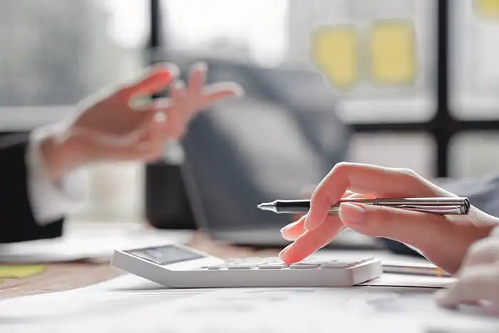 Hands using a calculator and pen during a property buying consultation in Portugal