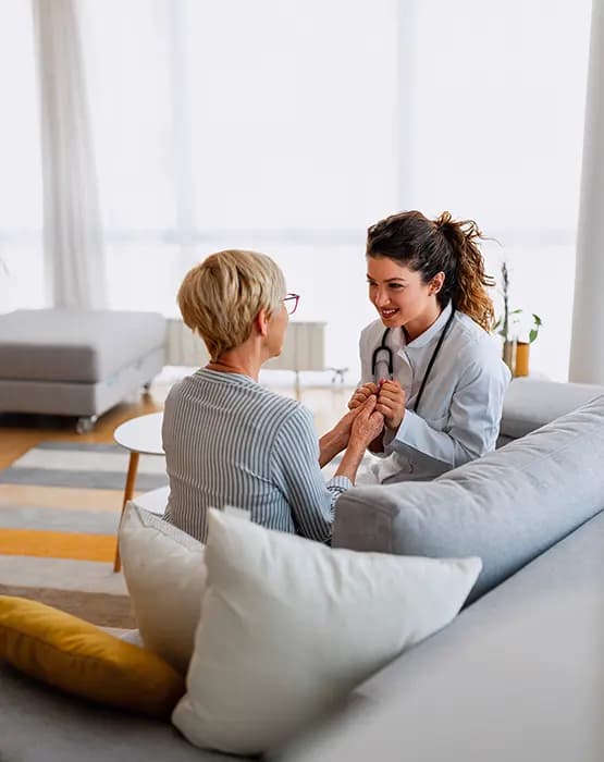 Doctor with a stethoscope comforting an older woman during a home visit