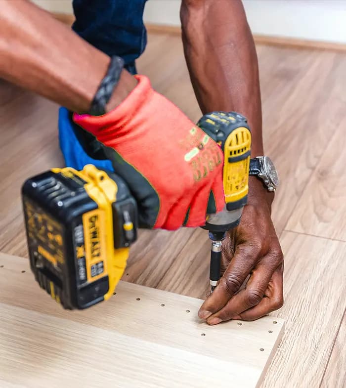 A tradesman fixing the wooden floor section with an electric screwdriver