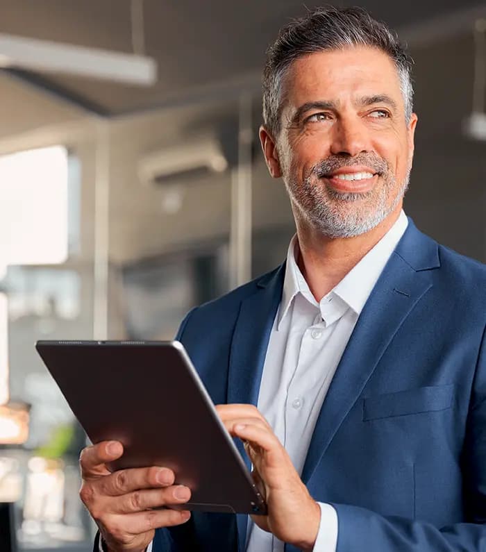 A confident 40 year old man with a tablet in his hands looking away and thinking of the future